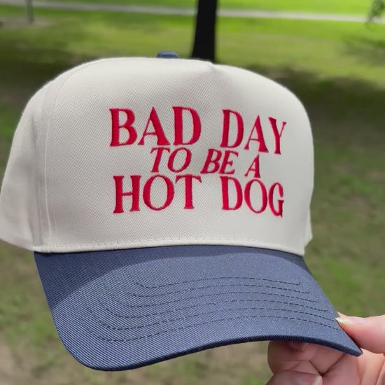Cap with 'Bad Day to be a Hot Dog' text held in front of a natural background