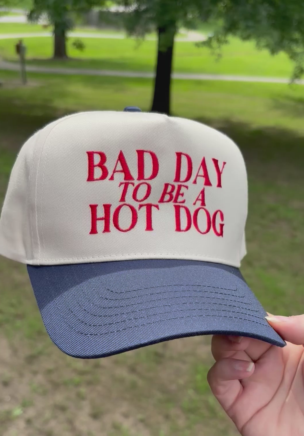 Cap with 'Bad Day to be a Hot Dog' text held in front of a natural background